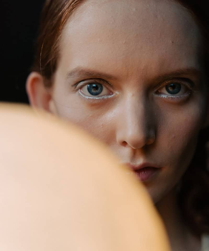 Blue-eyed woman close-up with freckles and red hair, natural beauty, detailed skin texture, soft lighting, fashion and beauty photography.