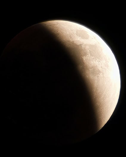 Partial lunar eclipse showing the moon's surface illuminated and shadowed.
