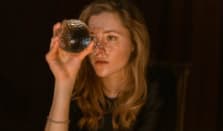 Elegant woman sipping red wine at a social event, stylish attire, warm ambiance.