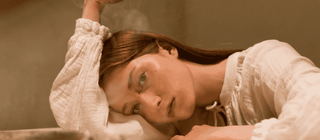 Soft-focused woman lying on sofa in cozy home setting, relaxed mood, casual wear.