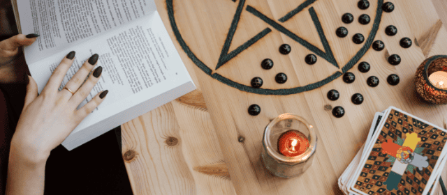 Intricate black pentagram symbols and tarot cards on a wooden table for spiritual and mystical practices.