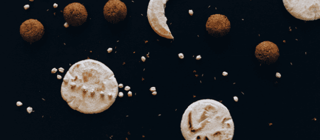 Oatmeal cookies with chocolate and white sugar sprinkles on dark background.